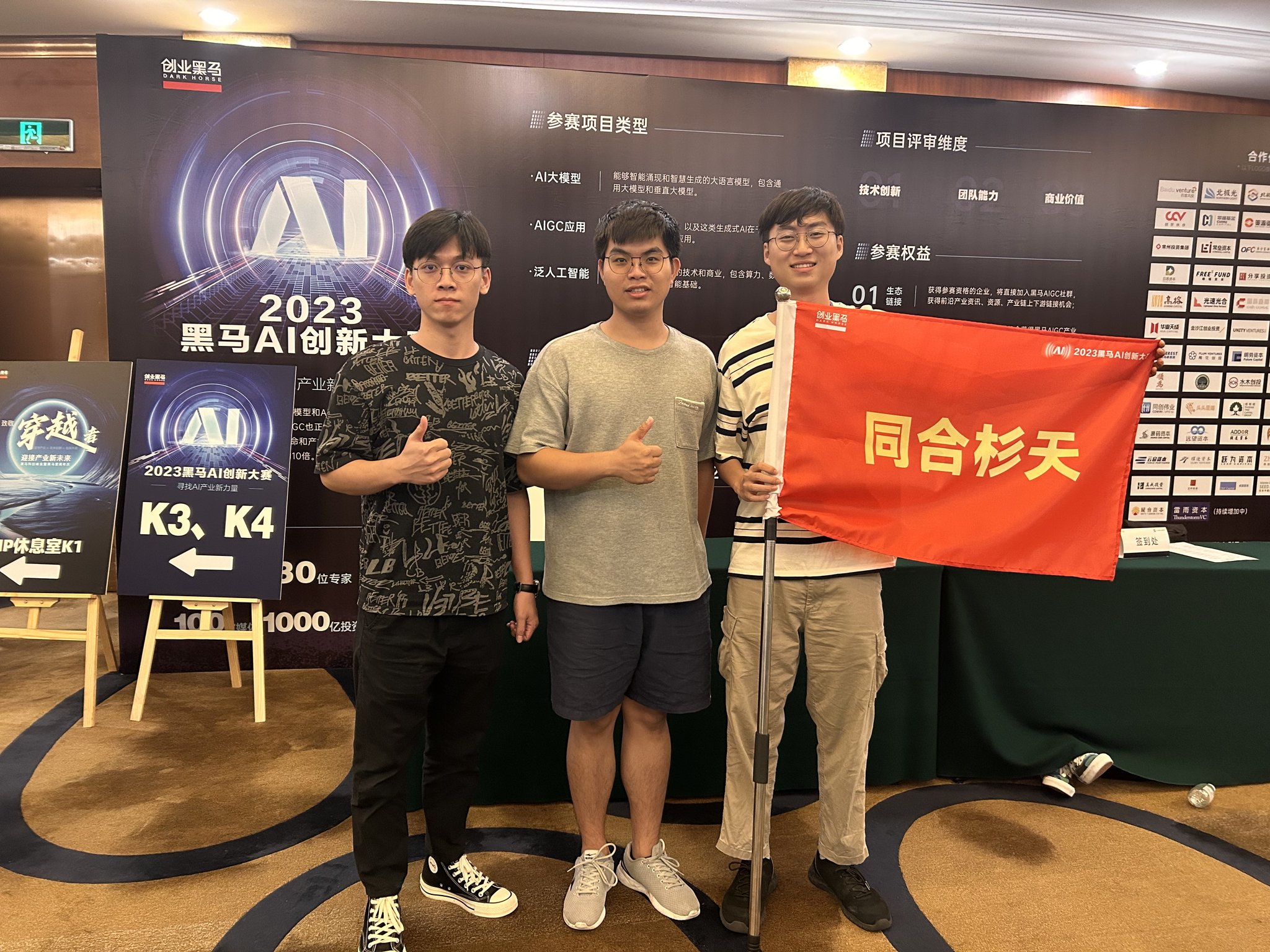 团队在 2023 黑马 AI 创新大赛现场举着同合杉天旗帜